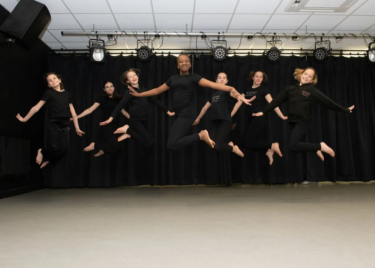 A group of young dancers caught mid-air during a contemporary class