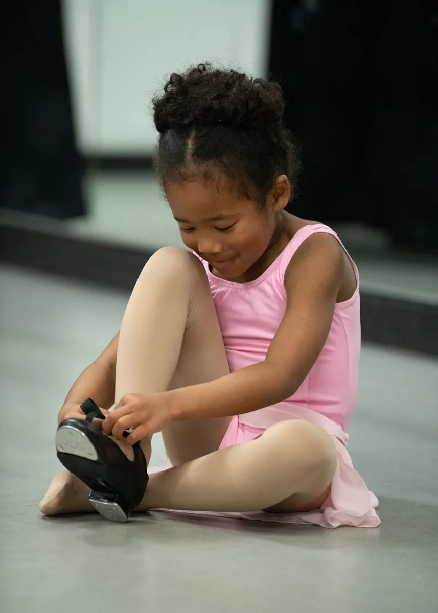 Young dancer in pink getting ready for a tap class
