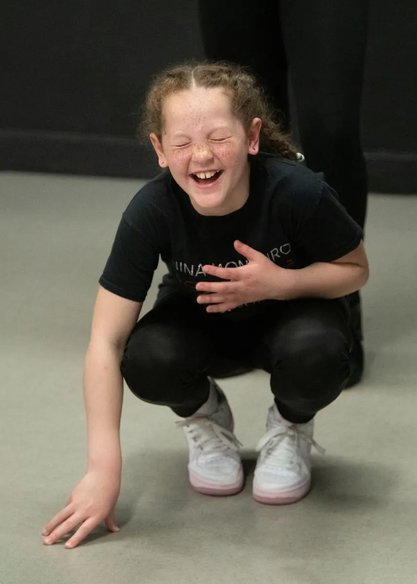 Young musical theatre dancer laughing in a playful floor pose